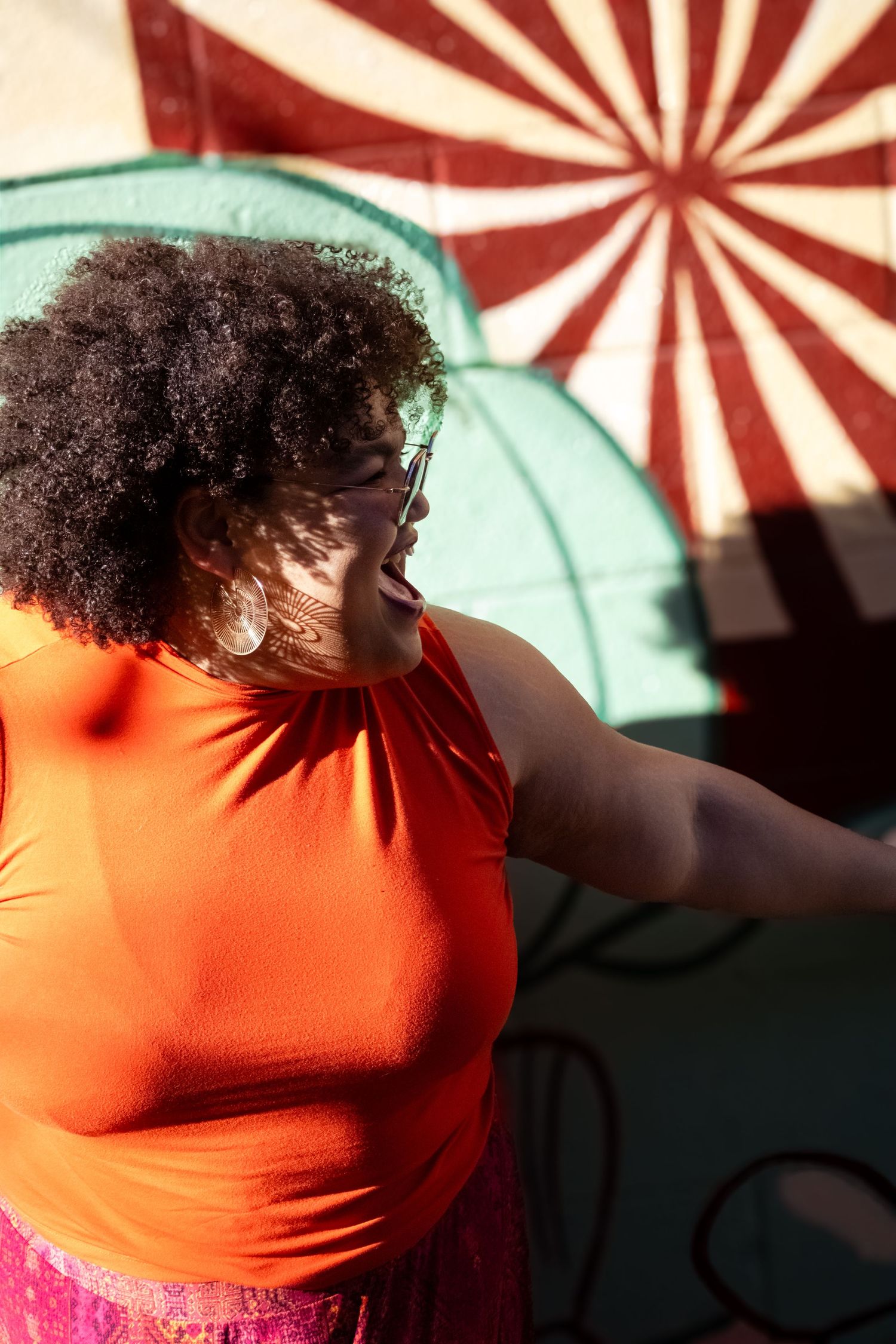 Person in orange shirt photographed against red and white striped background in artistic portrait series.