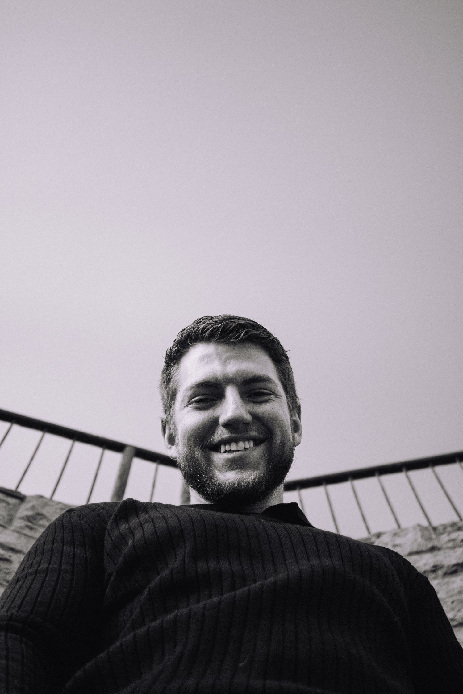 A black and white portrait series showing someone smiling at the camera from a low angle perspective.