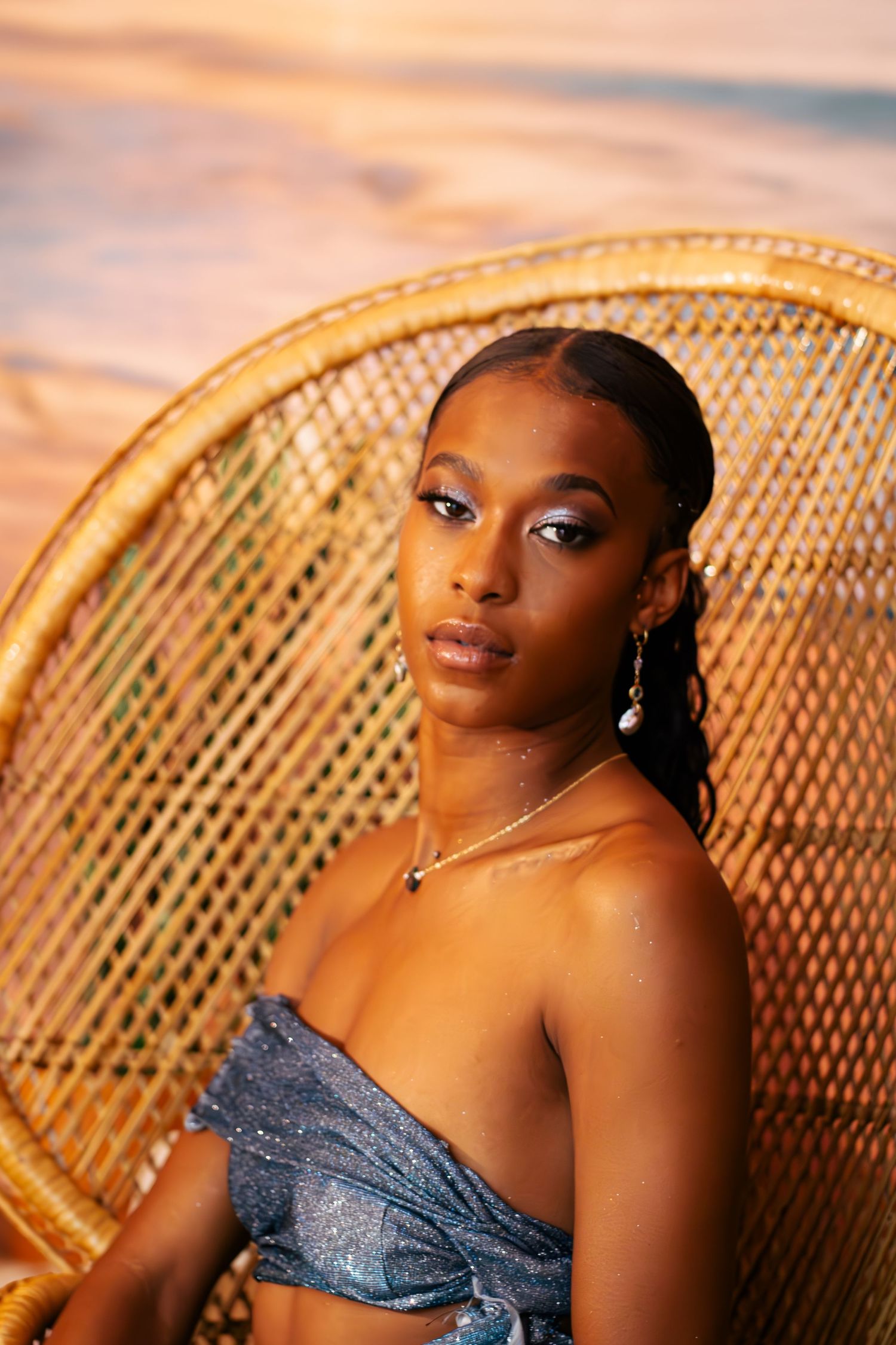 A series of warm-toned portrait photos showing someone posing on a wicker peacock chair at sunset.