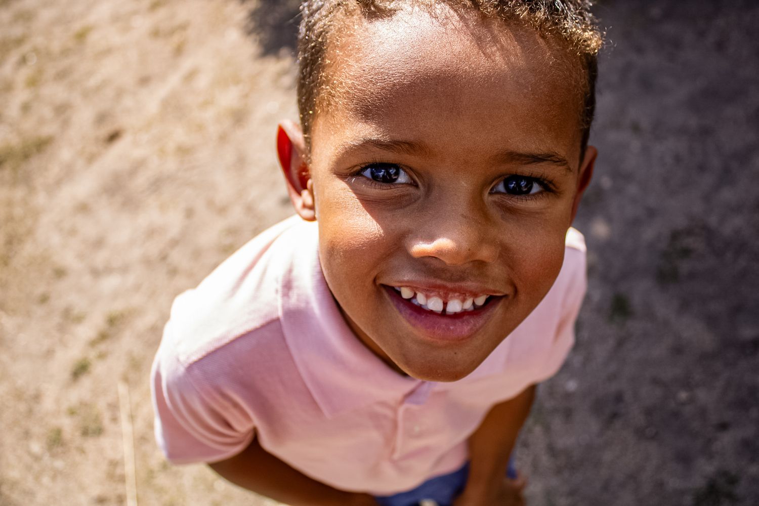 A child in pink clothing smiles warmly against a neutral beige background.