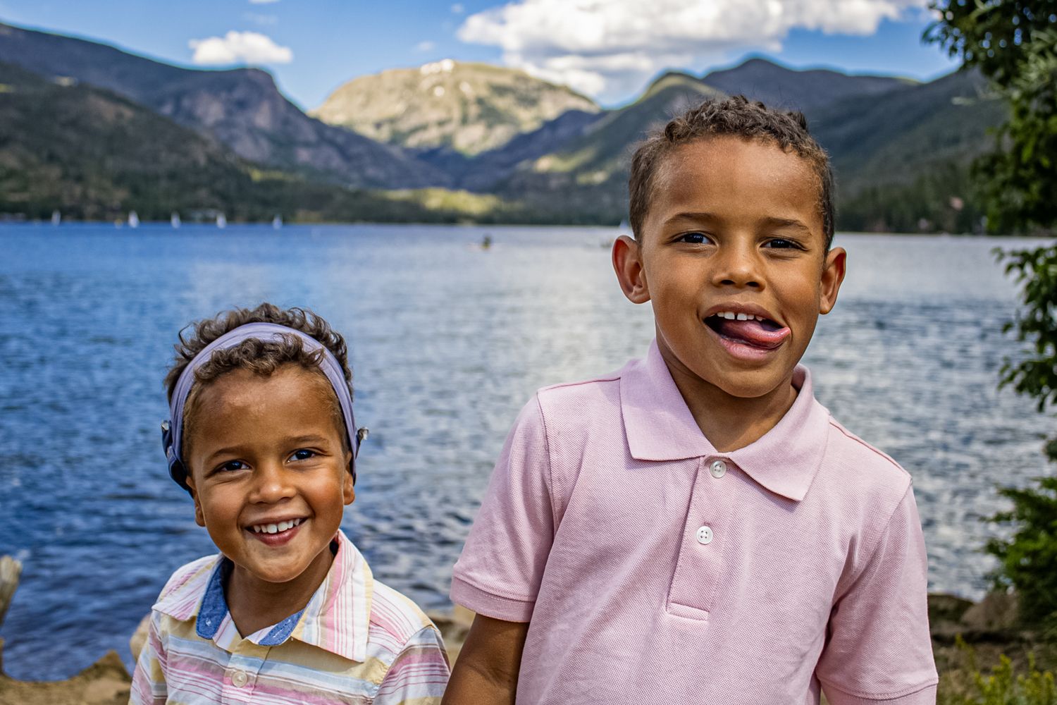 People smile and laugh together on a sunny day by a mountain lake with blue skies and scenic views.