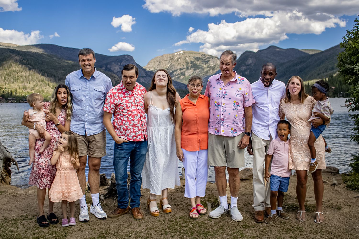 Family group photo by a mountain lake with scenic Rocky Mountain peaks in the background.