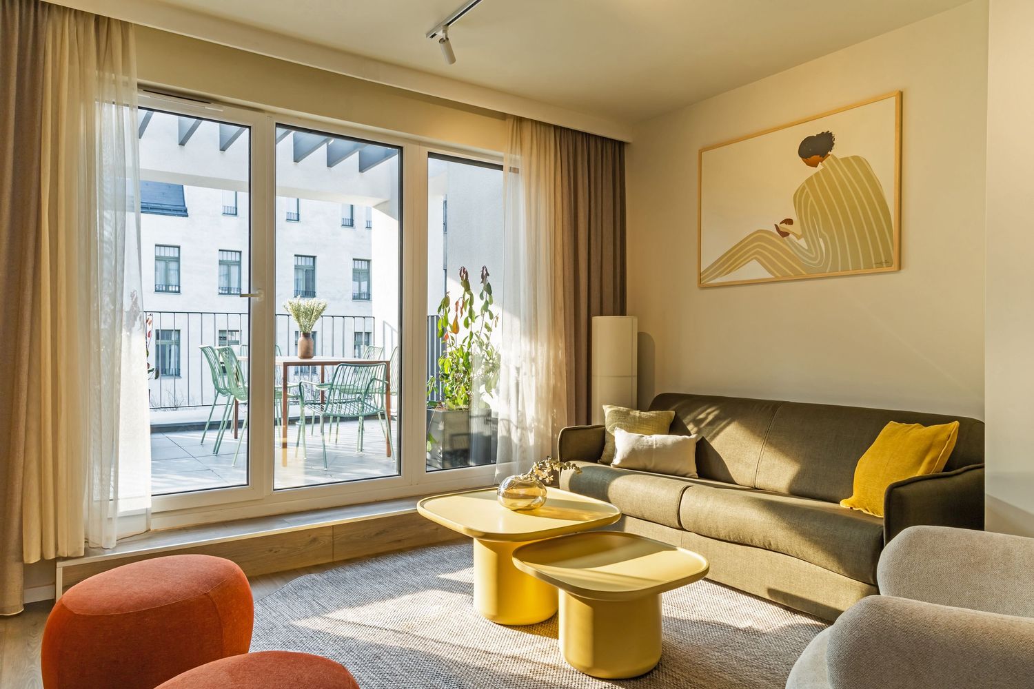 Contemporary living room with gray sofa, yellow coffee tables, large windows, and a balcony with city views.