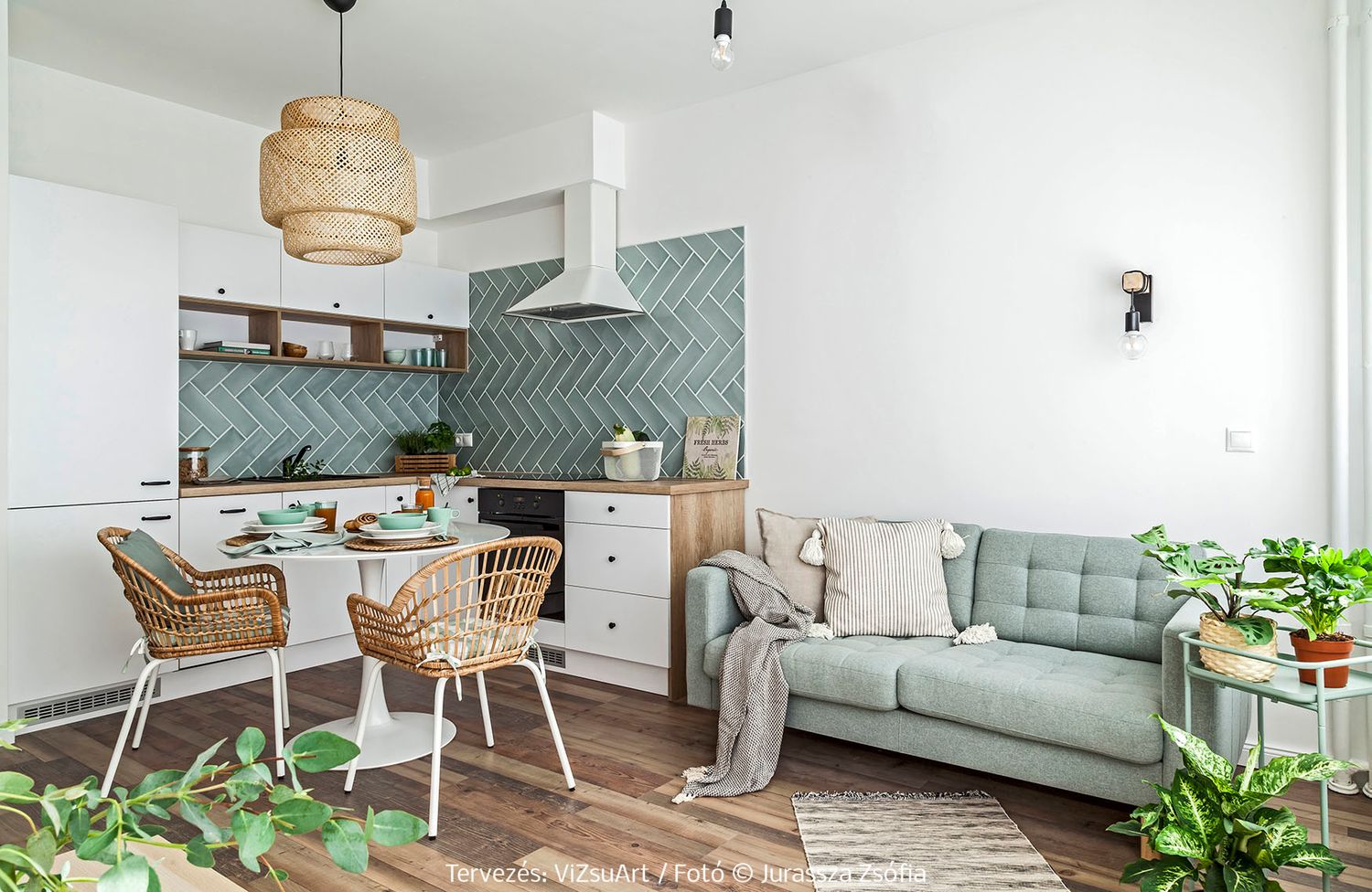 Modern Scandinavian open-plan kitchen and living room with sage green sofa and herringbone tile backsplash.