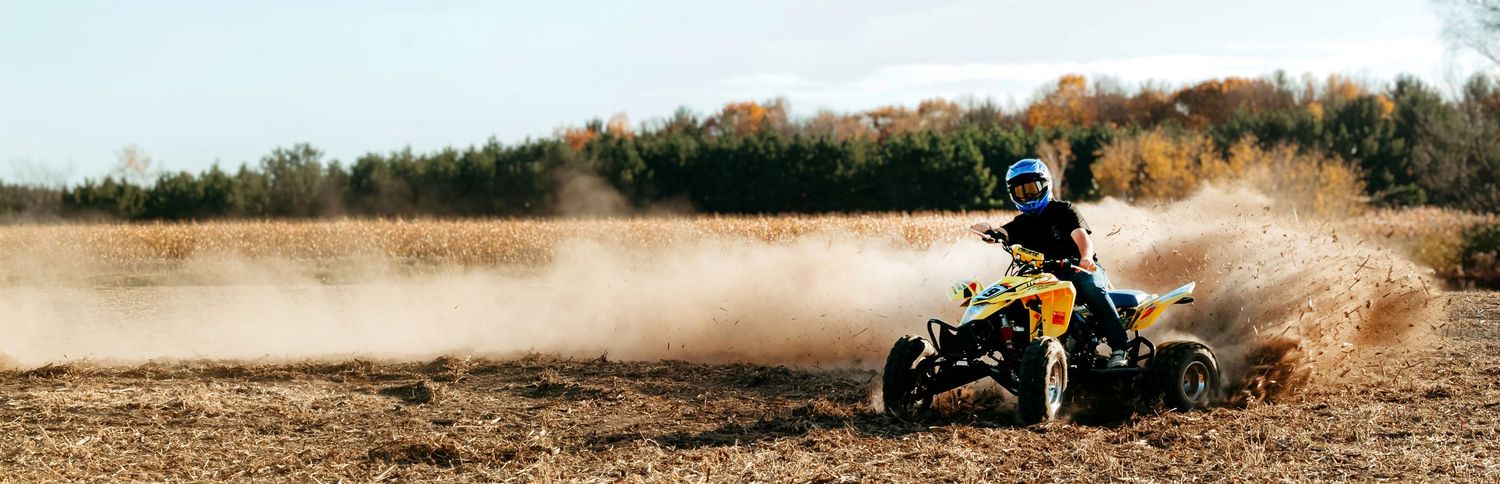 Dirt bike rider kicks up a dramatic cloud of dust while racing through an off-road desert track.