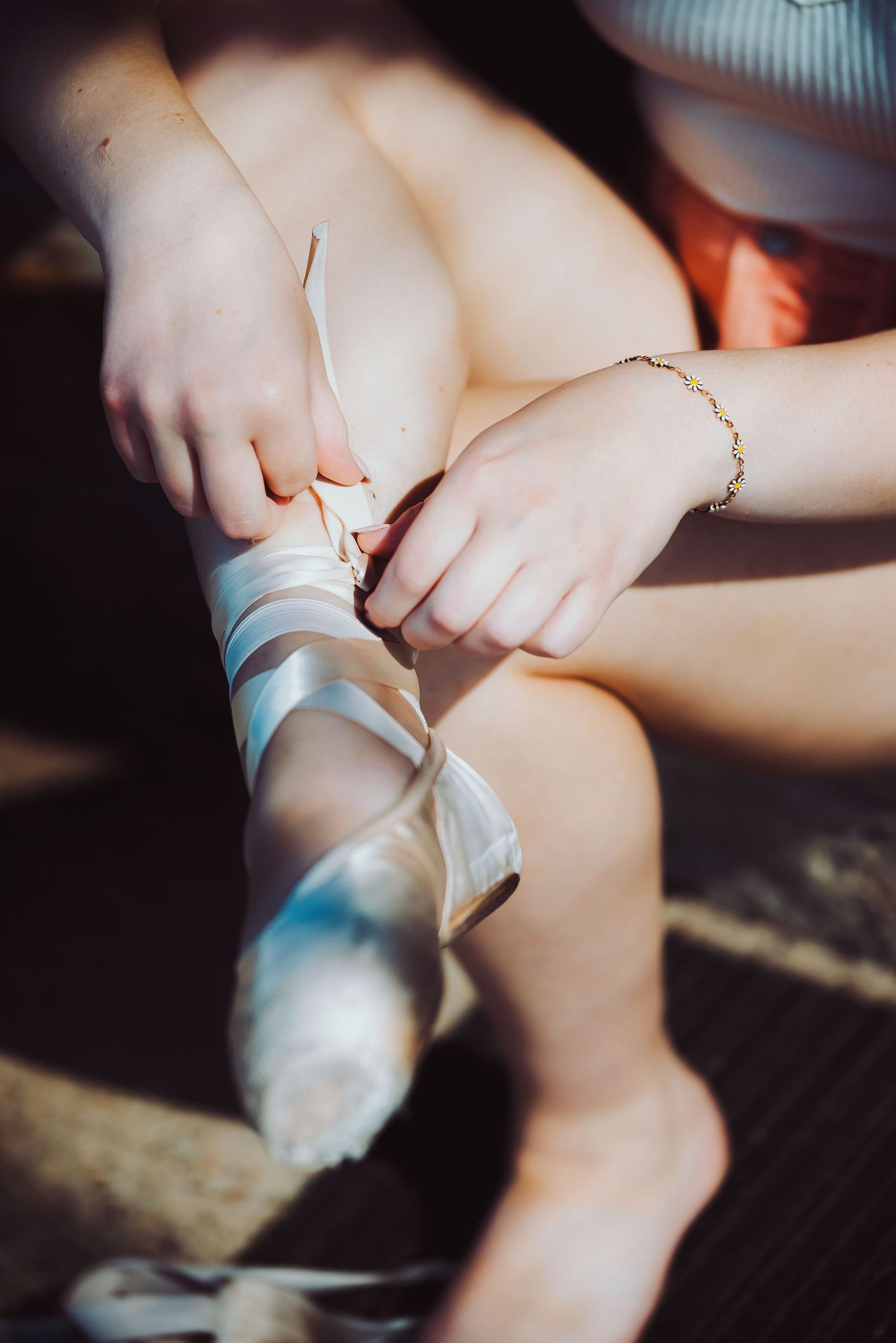 Close-up shots show delicate hands adjusting silver ballet slippers against a dark background.