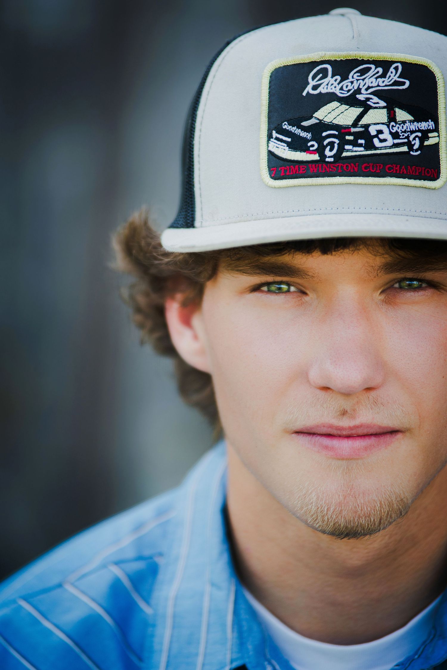A close-up shot shows a person wearing a Dale Earnhardt racing cap and blue striped shirt.