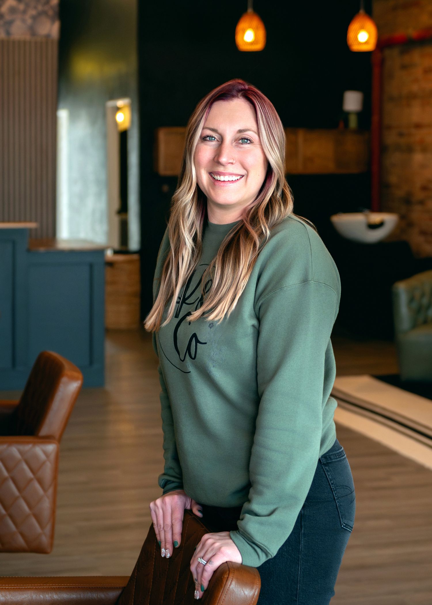 Professional portrait in a cozy restaurant interior with warm pendant lighting and leather seating.