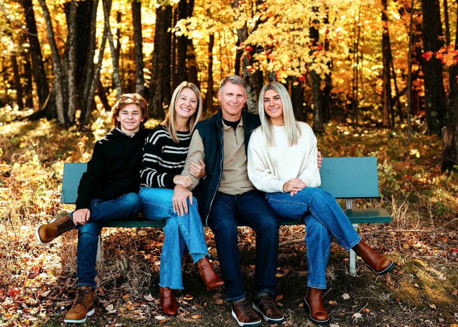 A group sits together on a blue bench surrounded by vibrant fall foliage with golden yellow leaves in the background.