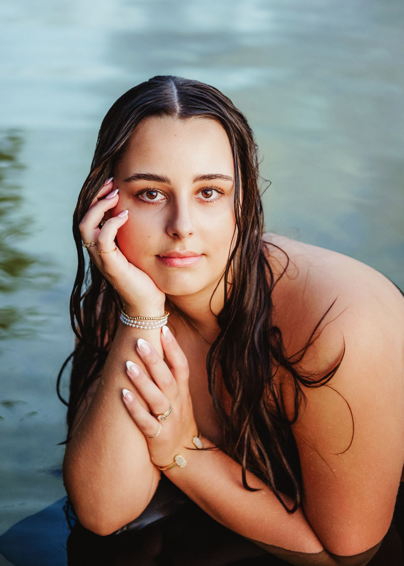 Portrait series showing ethereal poses near water with soft lighting and flowing dark hair.
