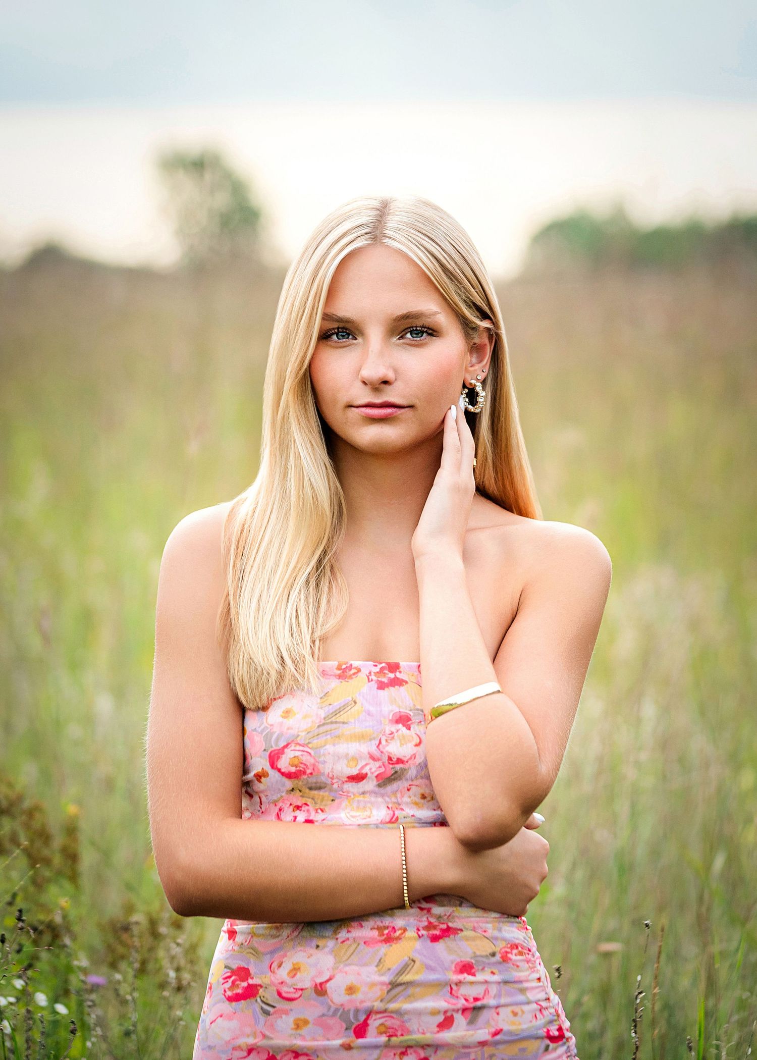 Portrait series of a person in a floral top posing in a sunny meadow with natural lighting.