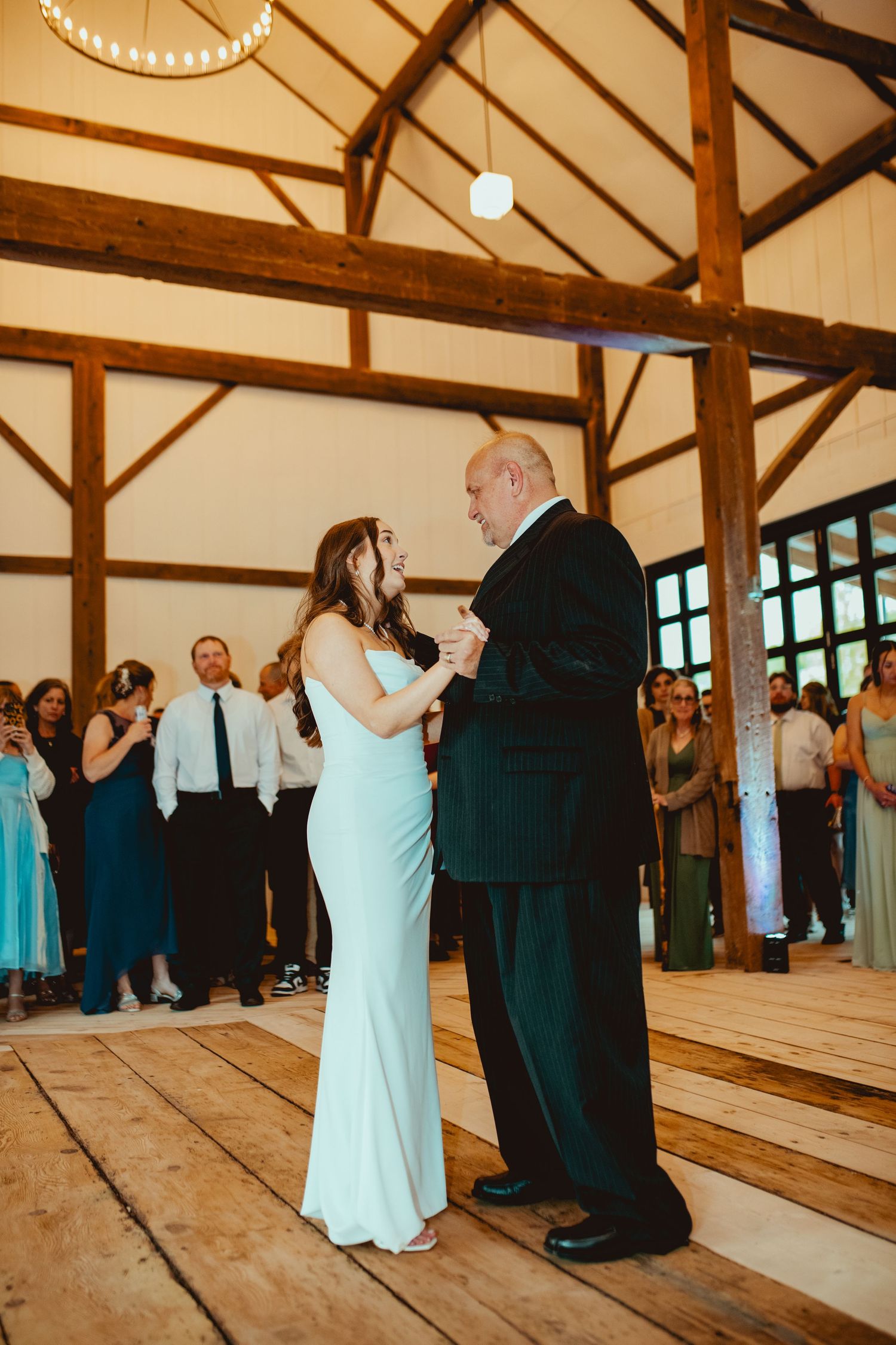 Wedding reception in a rustic wooden barn venue with exposed beams and wooden floors.