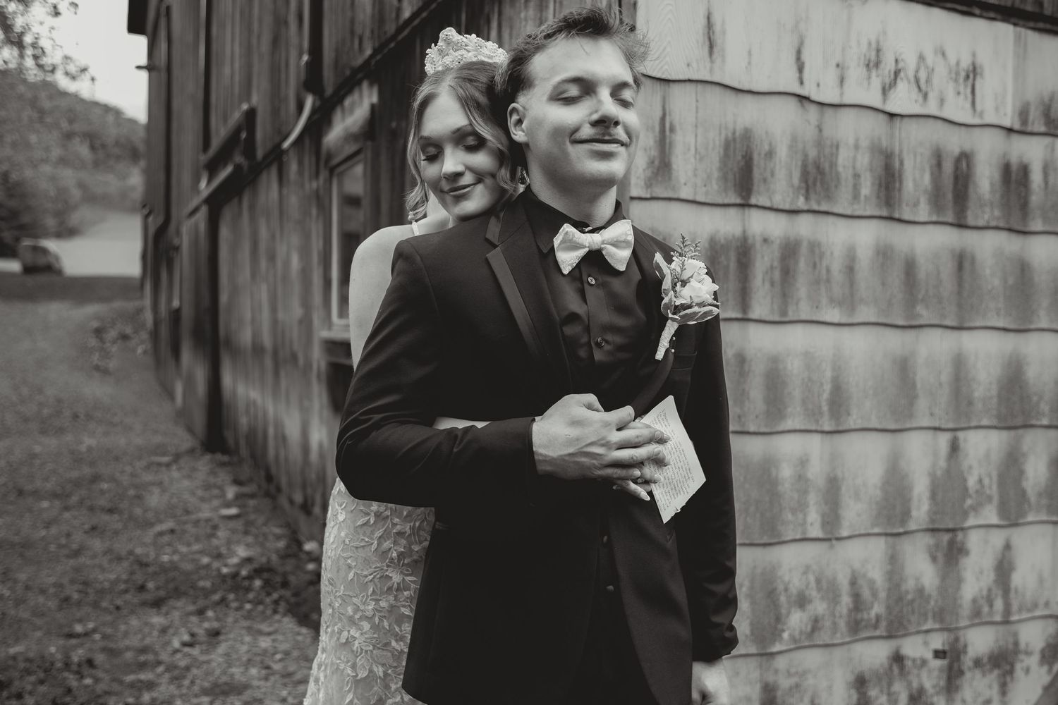 A black and white collage of wedding moments showing intimate poses against a rustic barn wall background.