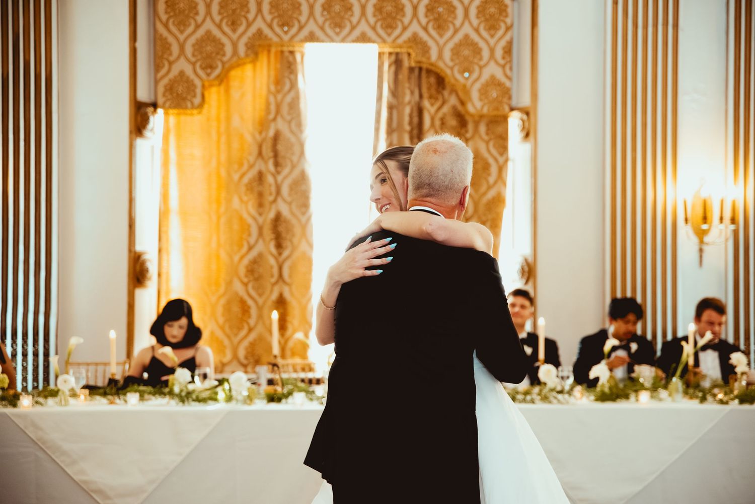 Elegant wedding reception setup with gold decor and dramatic lighting in formal ballroom.