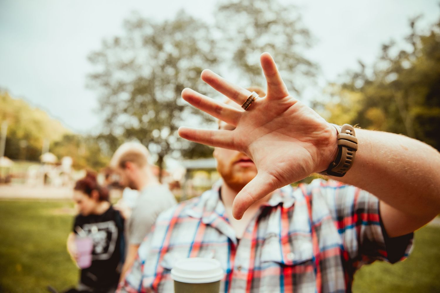 A series of hands making peace signs against a sunny outdoor background with trees and grass.