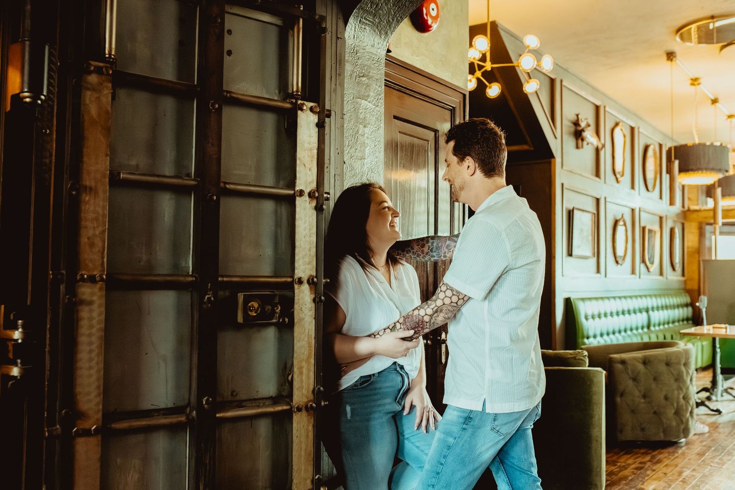 Couple laughing together in a stylish bar with green booths and industrial decor.