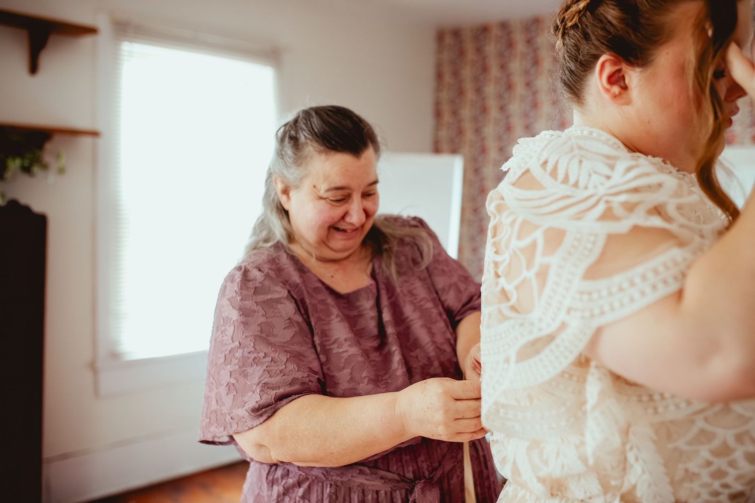 Two women embrace and smile joyfully during a special wedding moment.