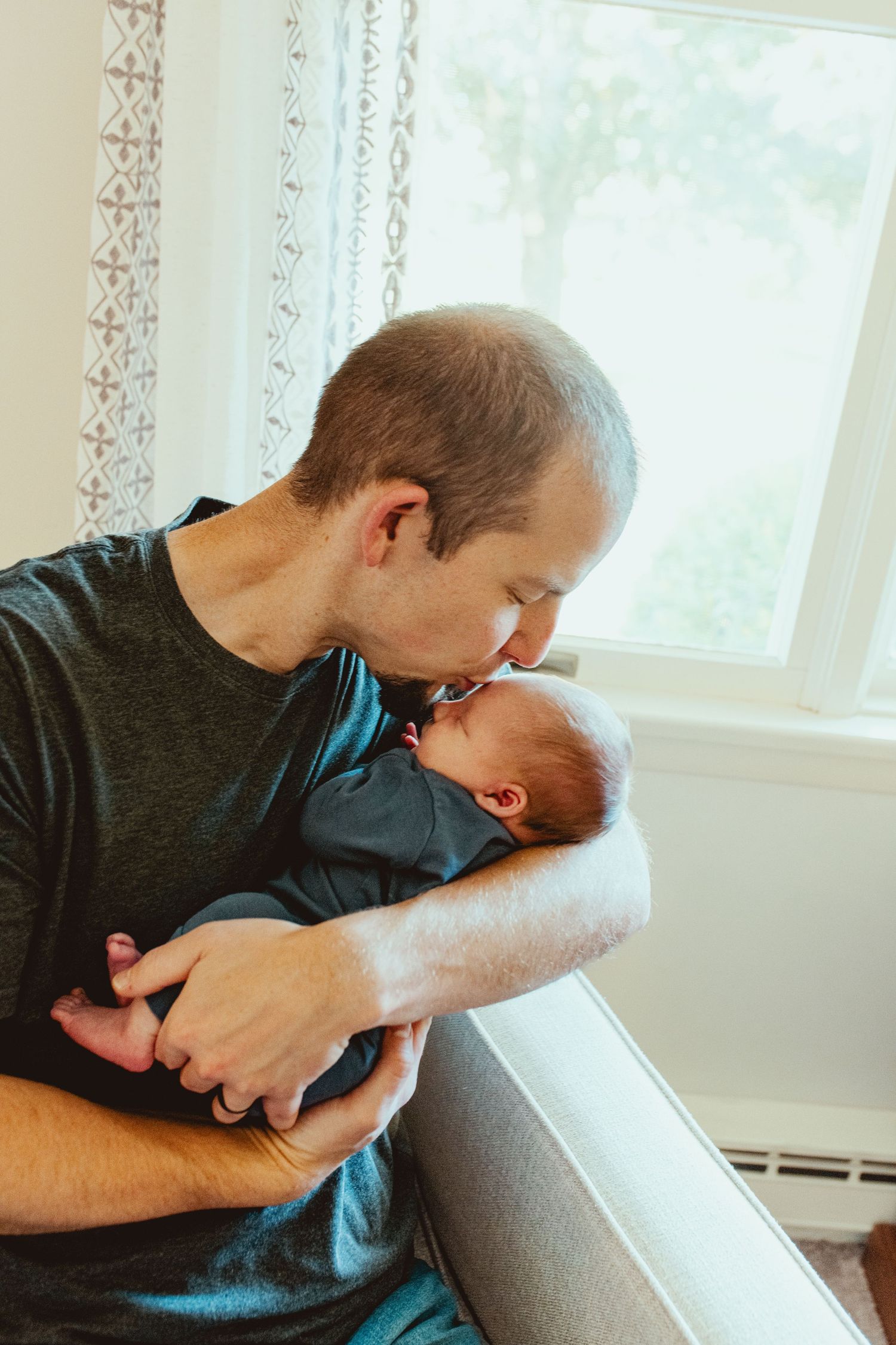 A tender moment between parent and infant as they share a quiet embrace by a sunlit window.