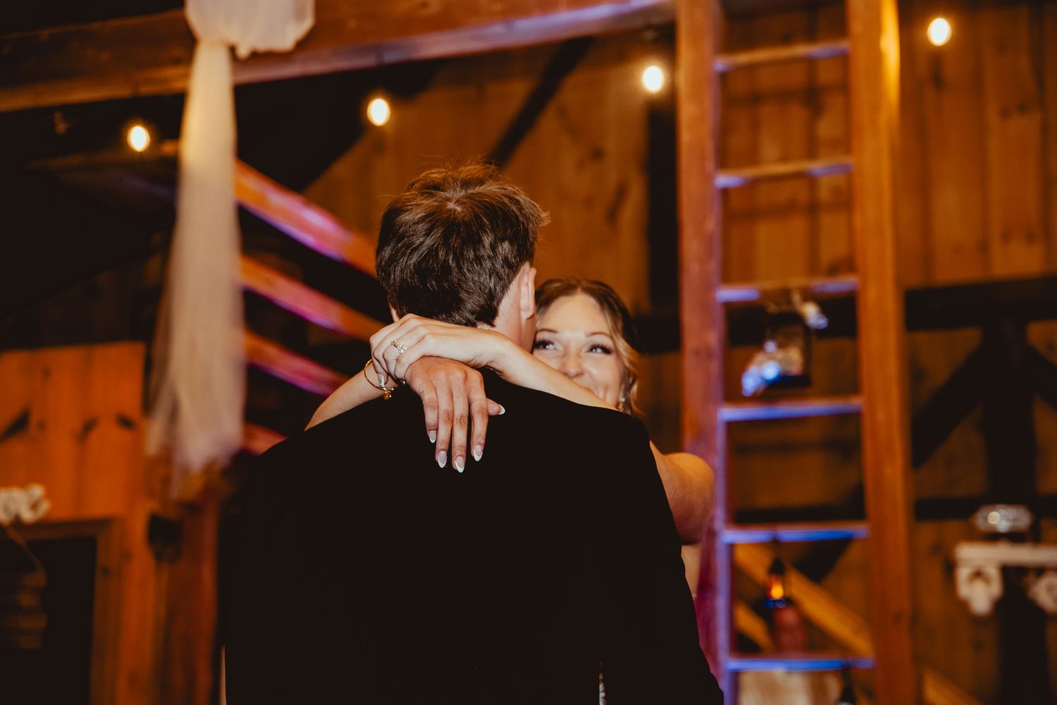 A series of romantic moments at a rustic barn wedding reception with warm lighting and festive decorations.