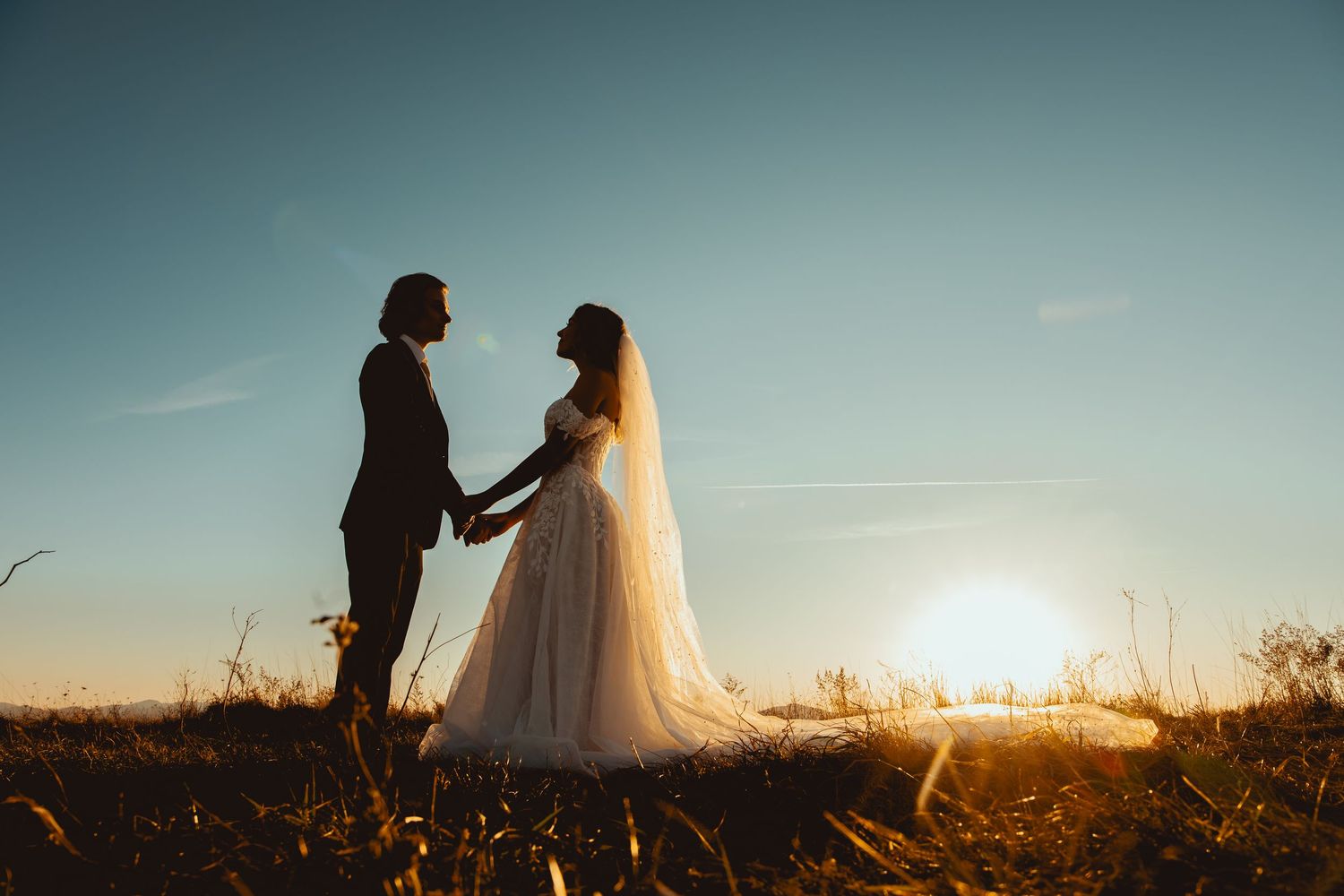 Silhouettes of couple against sunset sky in panoramic desert landscape.