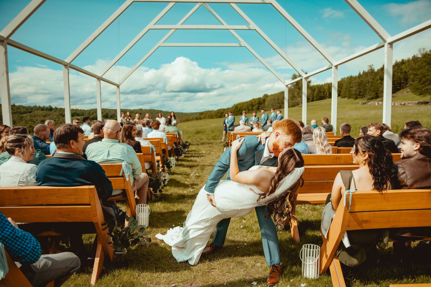 Modern clear tent wedding venue with wooden benches and scenic mountain views.