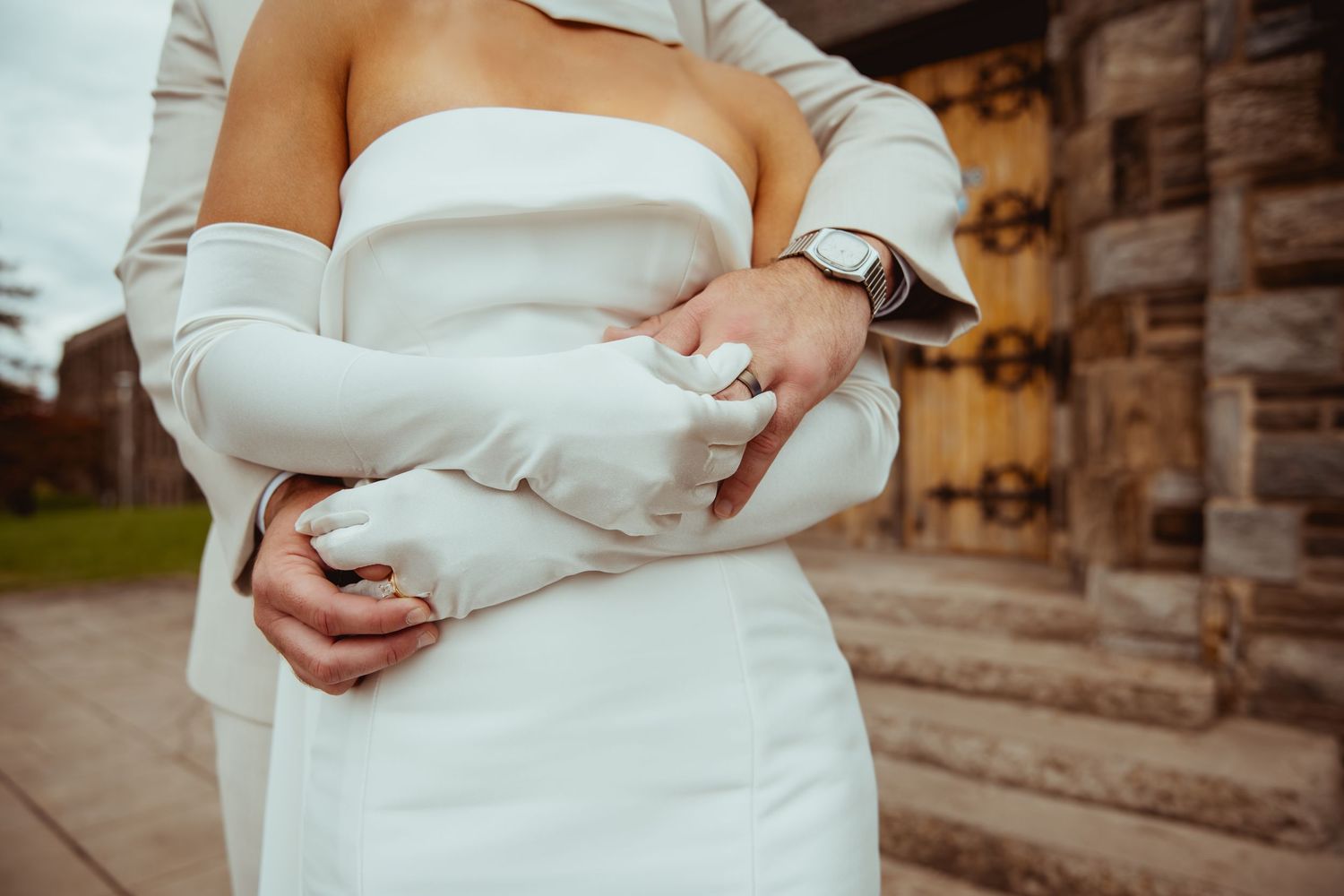 A romantic wedding couple embraces while standing on stone steps during an outdoor photo session.