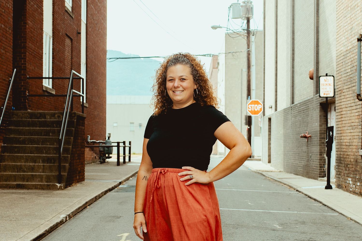 A person in a red dress poses confidently against urban brick walls in a series of outdoor fashion shots.