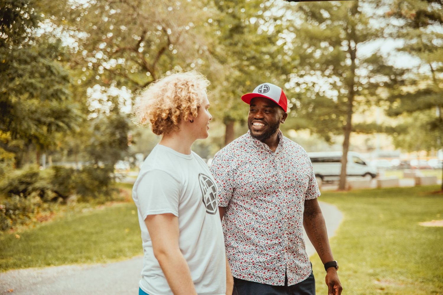 Two people walk together and share conversation in a sunny park setting during golden hour.