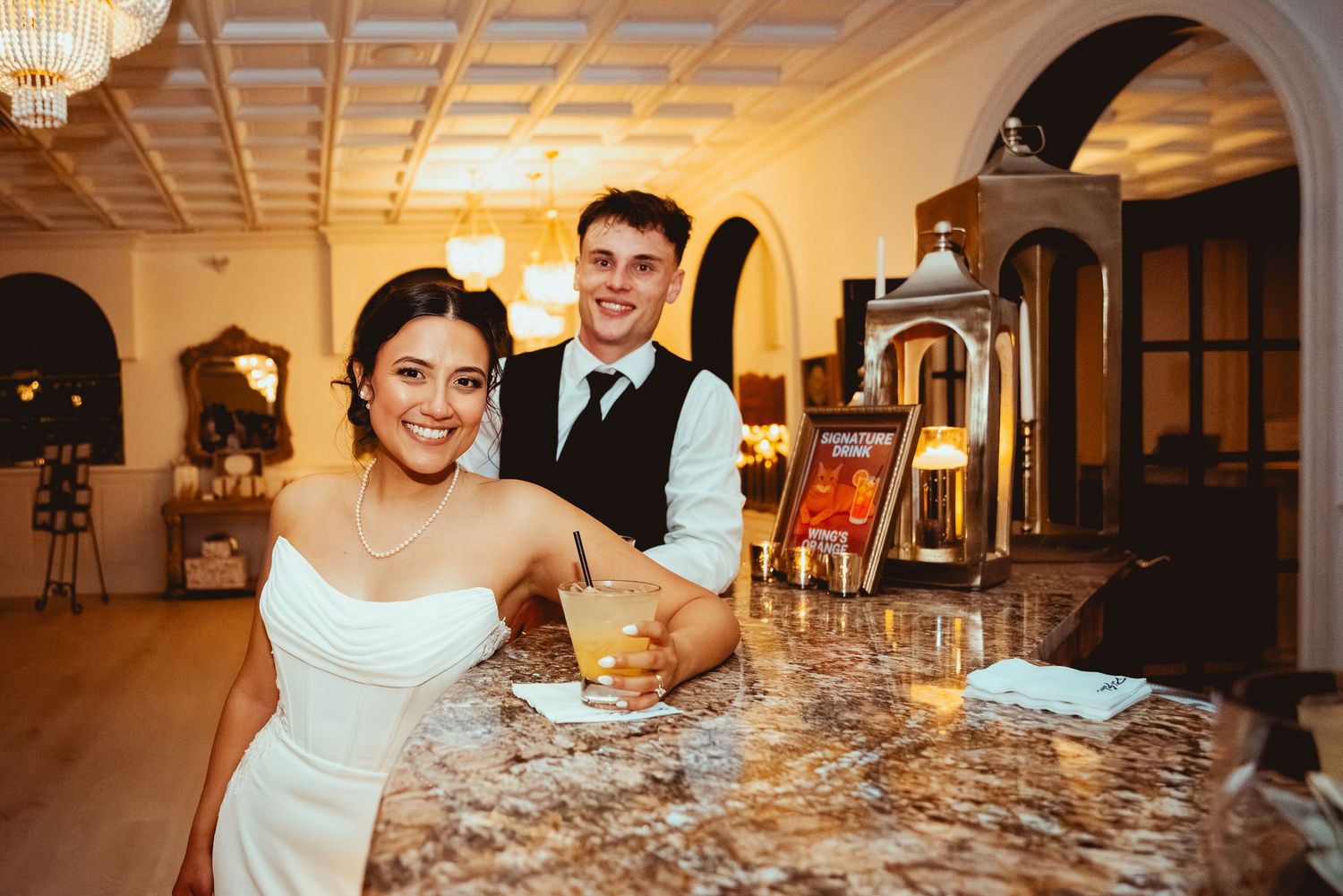 A wedding reception banquet hall with elegant table settings and warm lighting illuminating the ornate coffered ceiling.