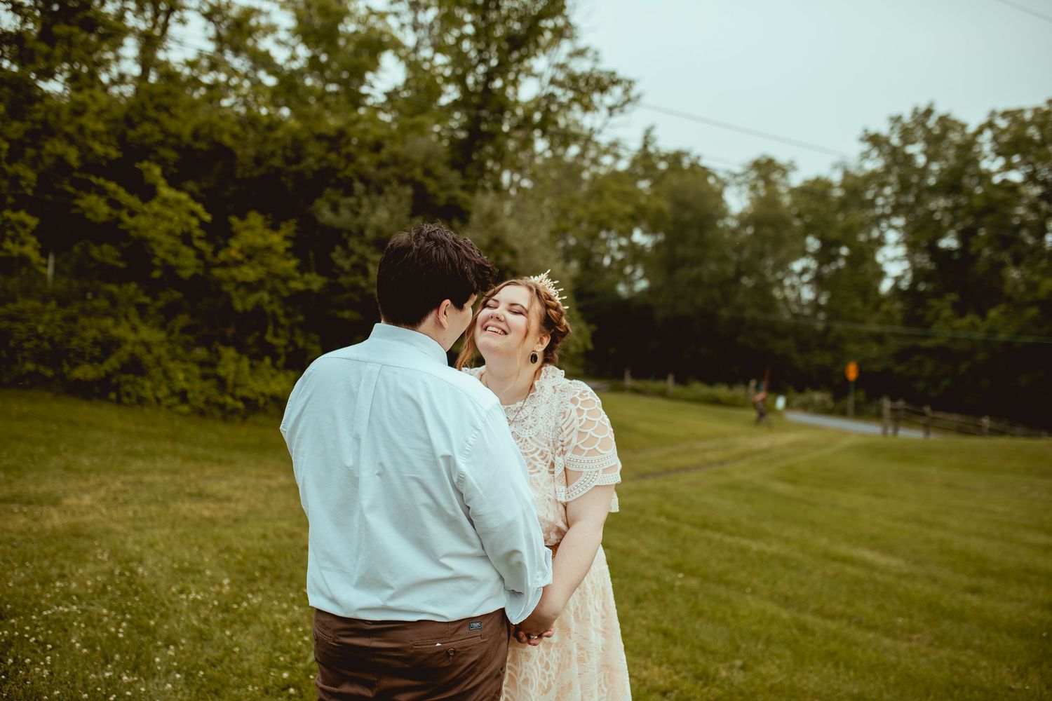 A couple shares a tender moment together on a grassy lawn during a summer evening.