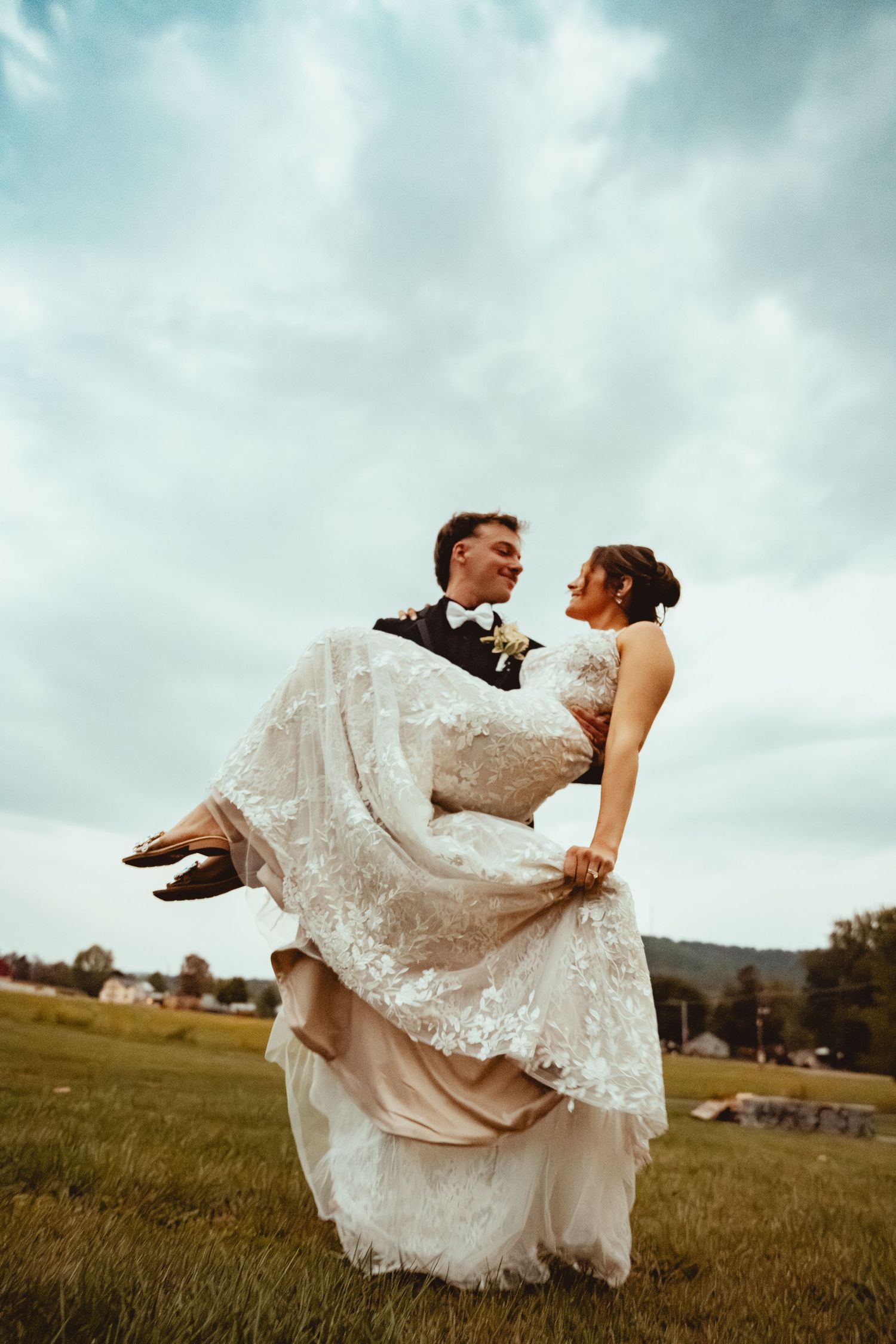 A couple shares a romantic dance move in a sunlit field.