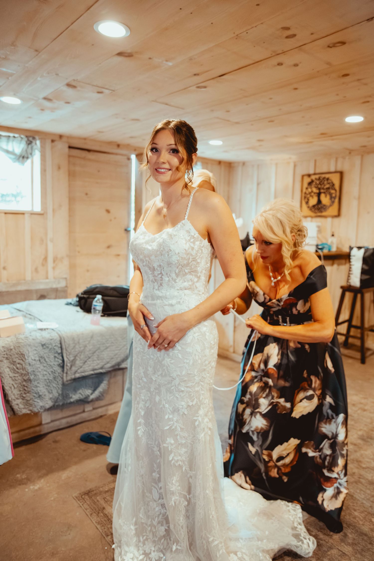 A wedding dress being laced up in a rustic wooden room with recessed lighting.