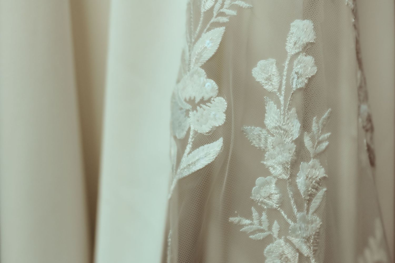 White floral embroidered pattern on sheer curtain fabric creates an elegant window treatment design.