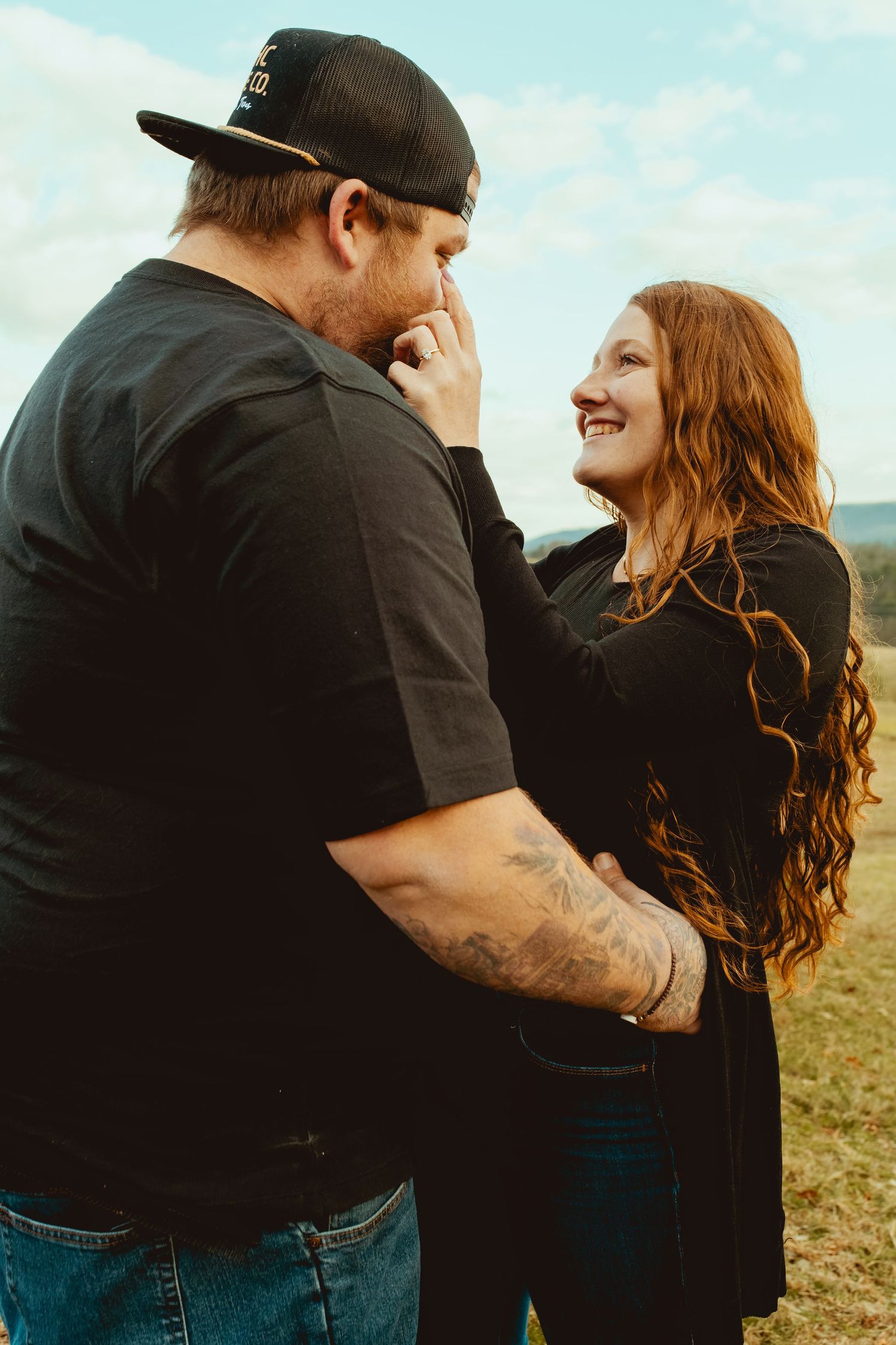 A couple embraces lovingly in a field during an intimate outdoor photo session at golden hour.