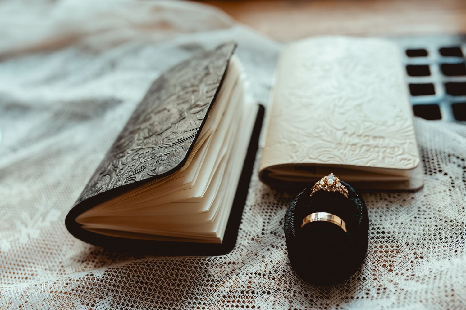 A collection of vintage books and rings arranged artistically on white lace fabric.