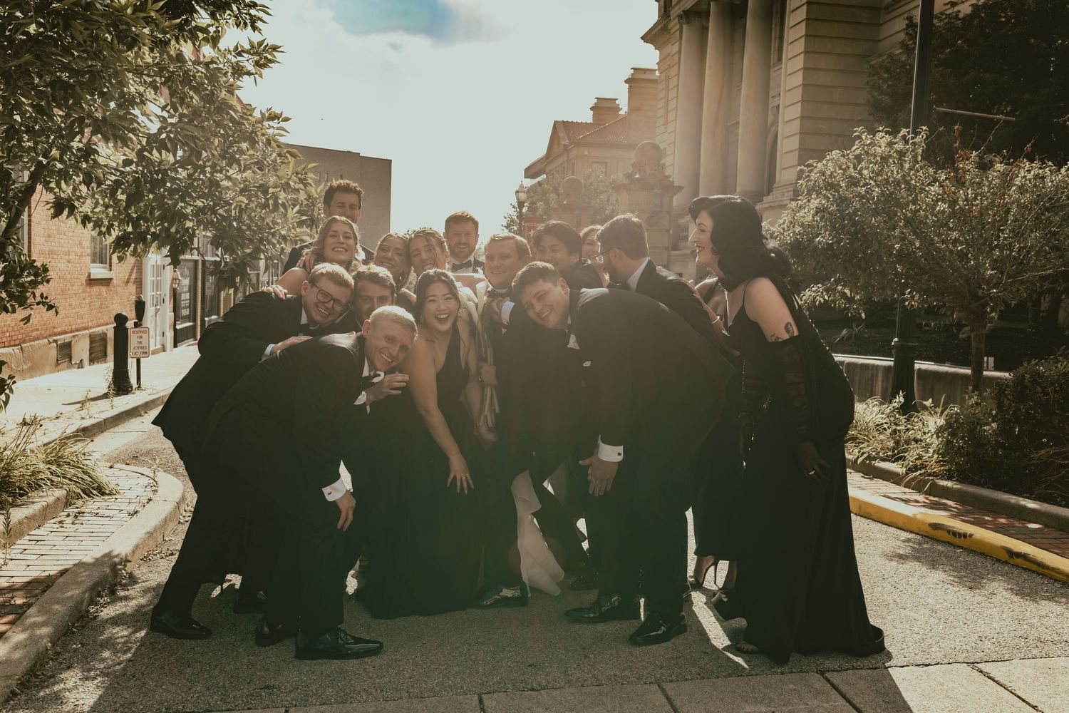Wedding party posing outdoors in front of classical stone columns and architecture.