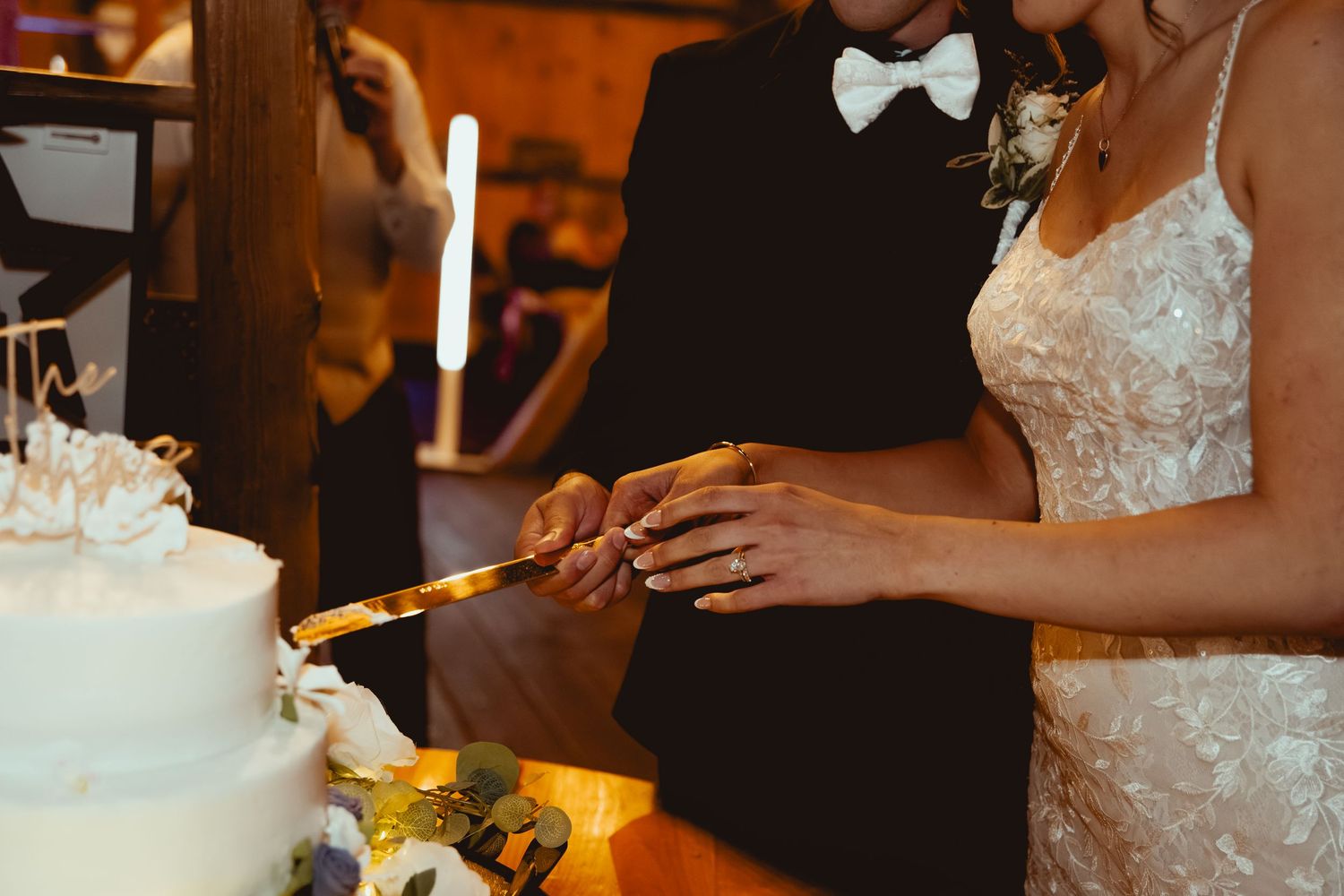 A wedding cake being cut with a silver knife at an elegant reception.