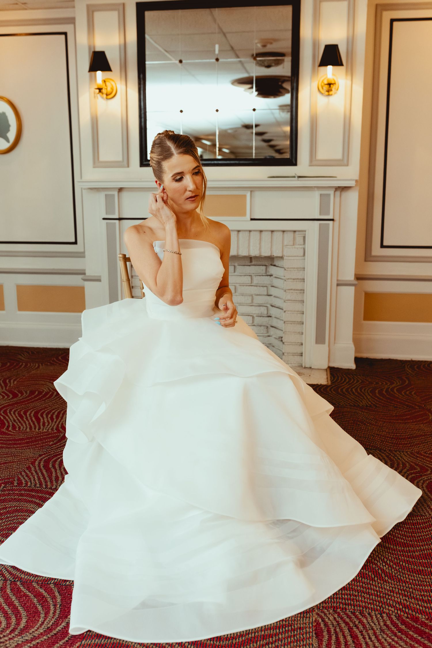 A stunning white wedding gown with voluminous ruffled layers swirls elegantly in an ornate hotel hallway.