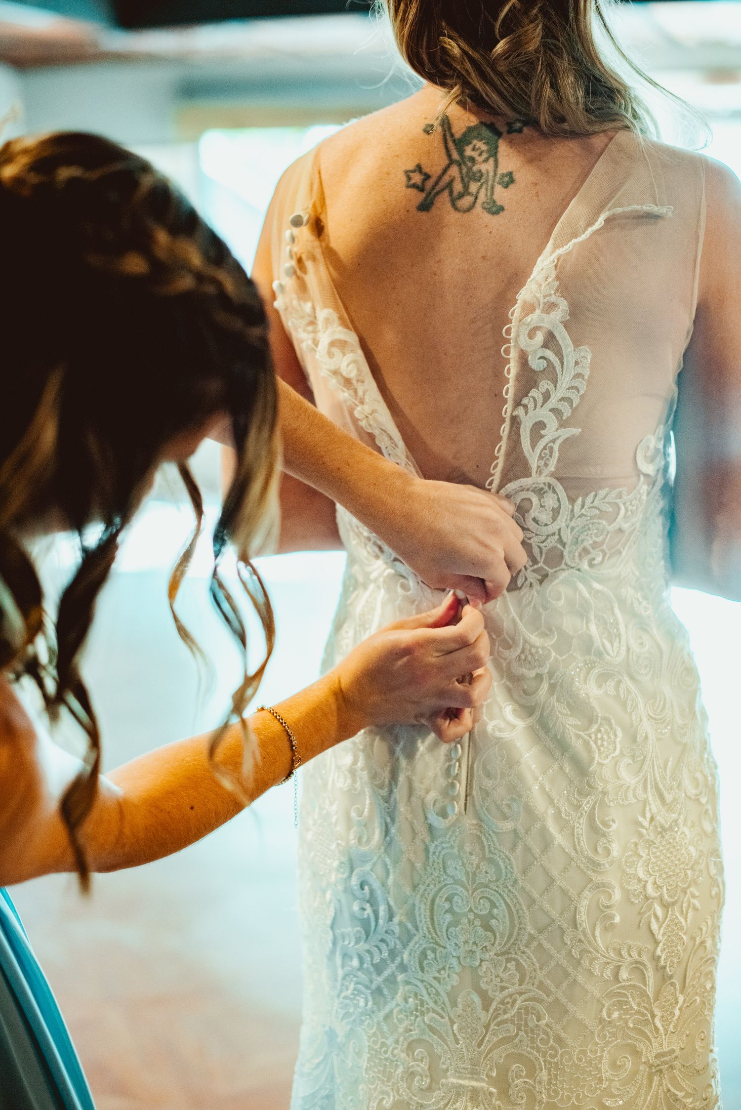Close-up shots showing intricate lace details and buttons on the back of an elegant white wedding dress.