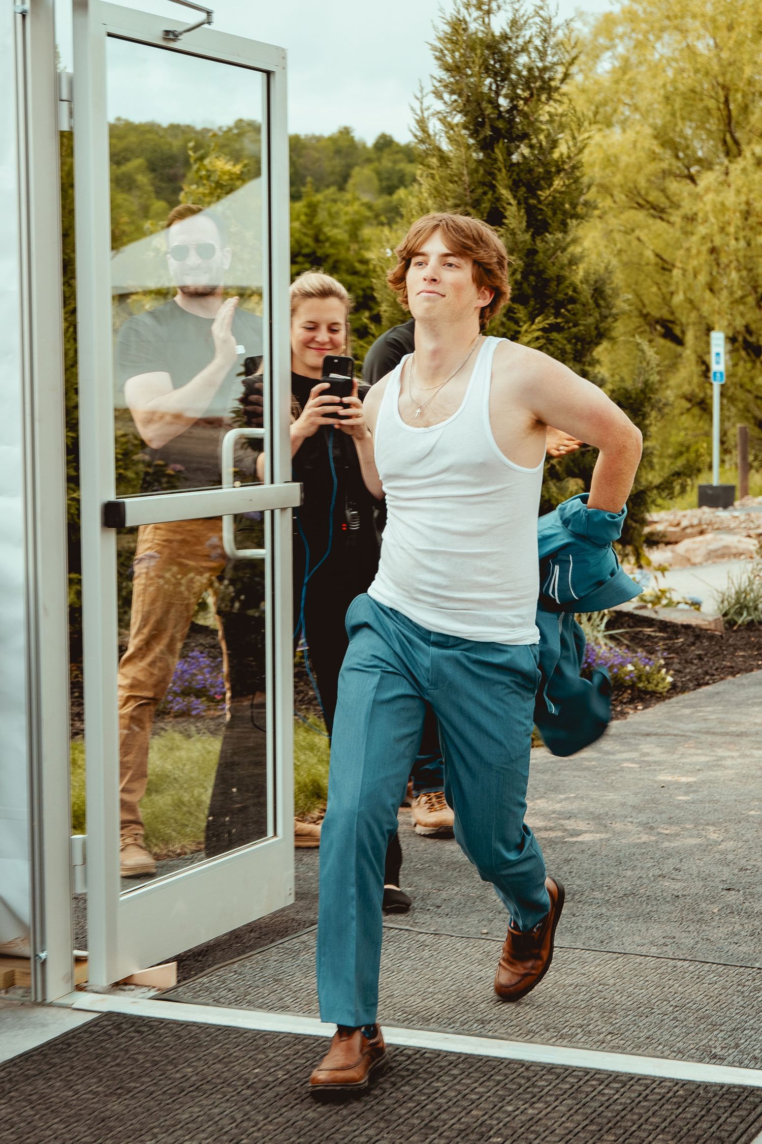 Dynamic dance moves captured at wedding venue entrance with glass doors.