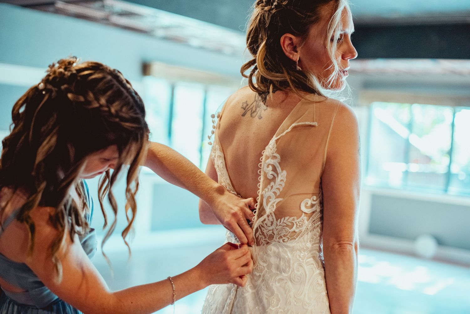 A series of photos showing the back of a wedding dress being laced up and adjusted by helping hands.