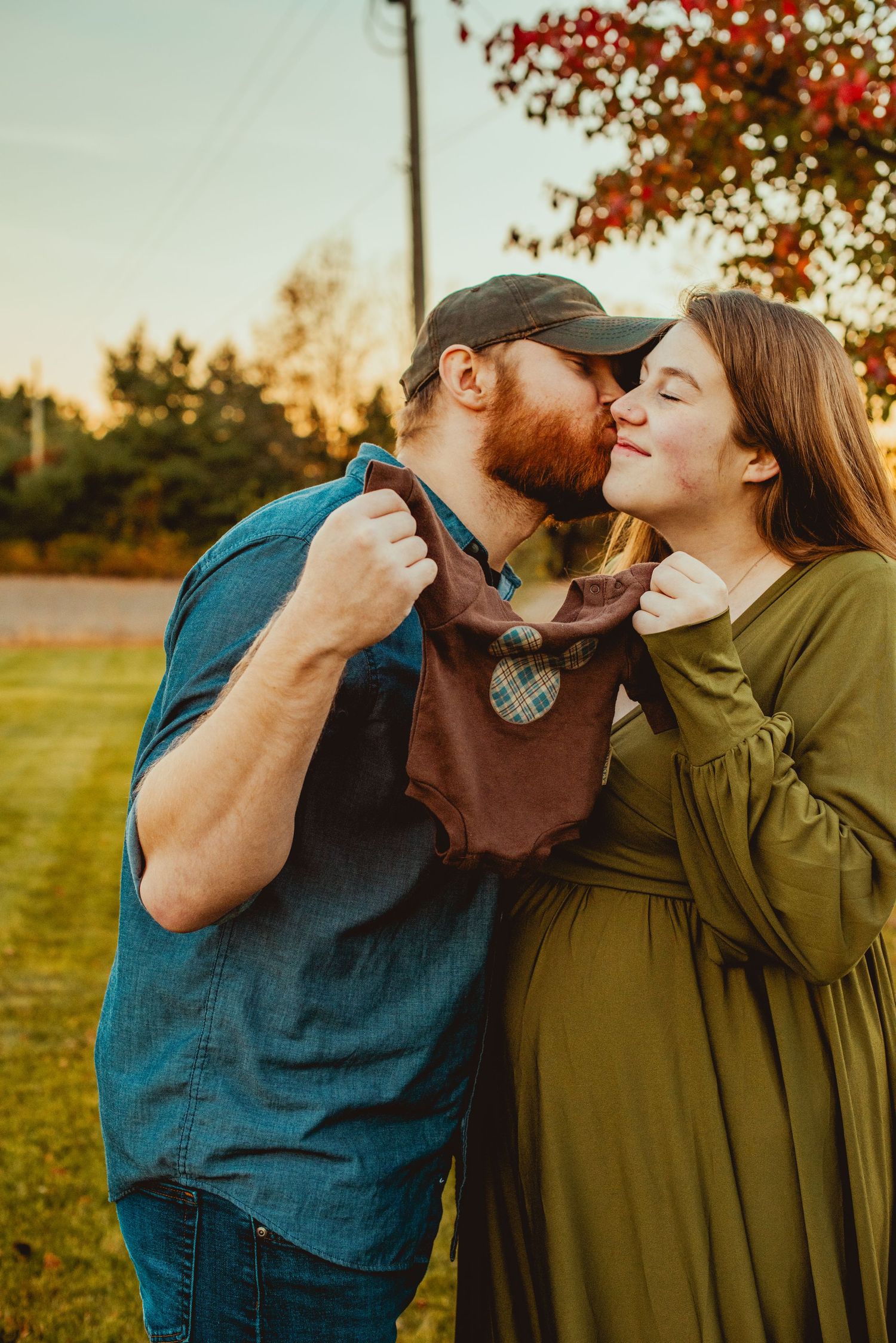 Romantic couple sharing tender moment in autumn setting with golden sunlight and fall foliage in background.