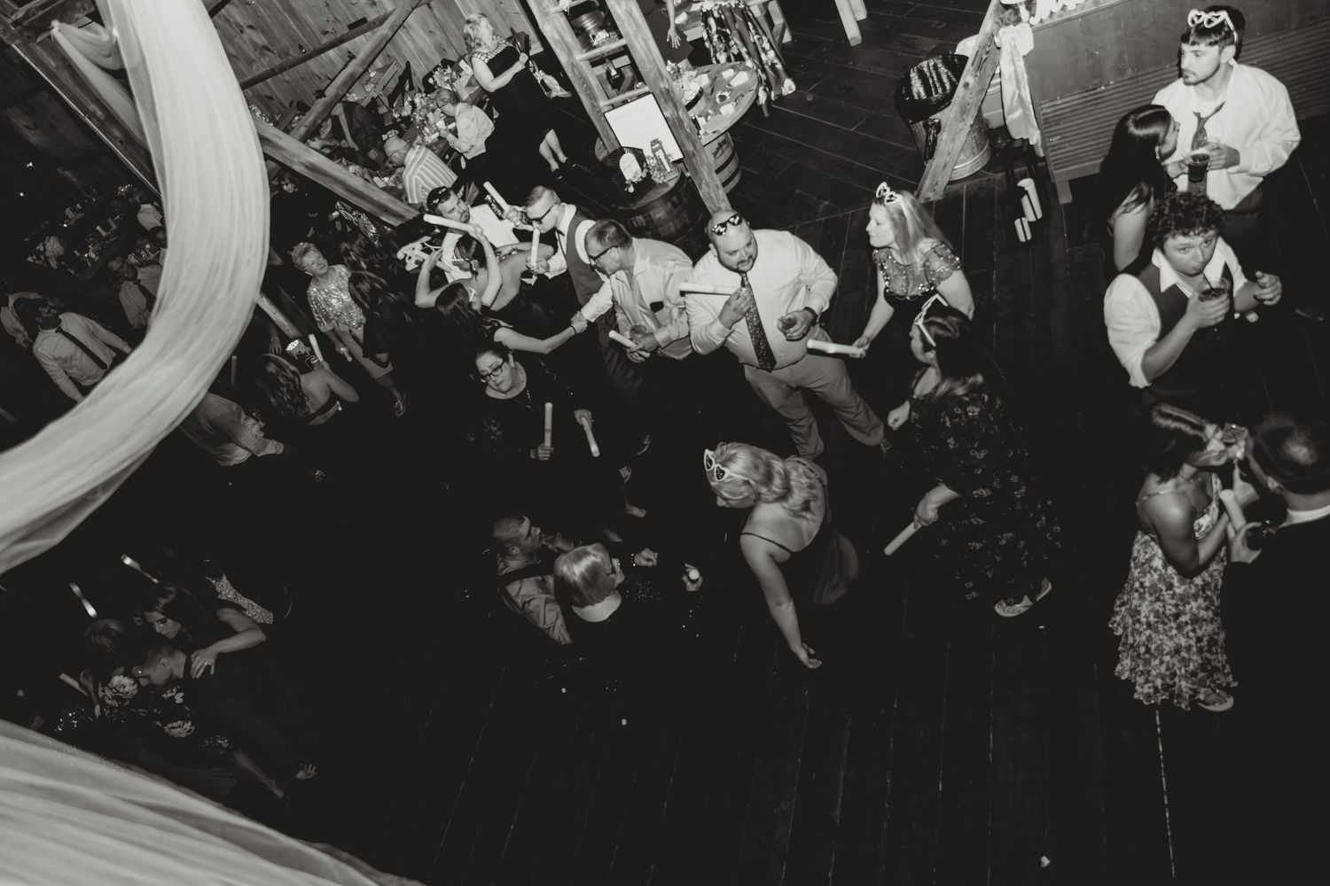 Black and white photo of wedding guests dancing at reception party.