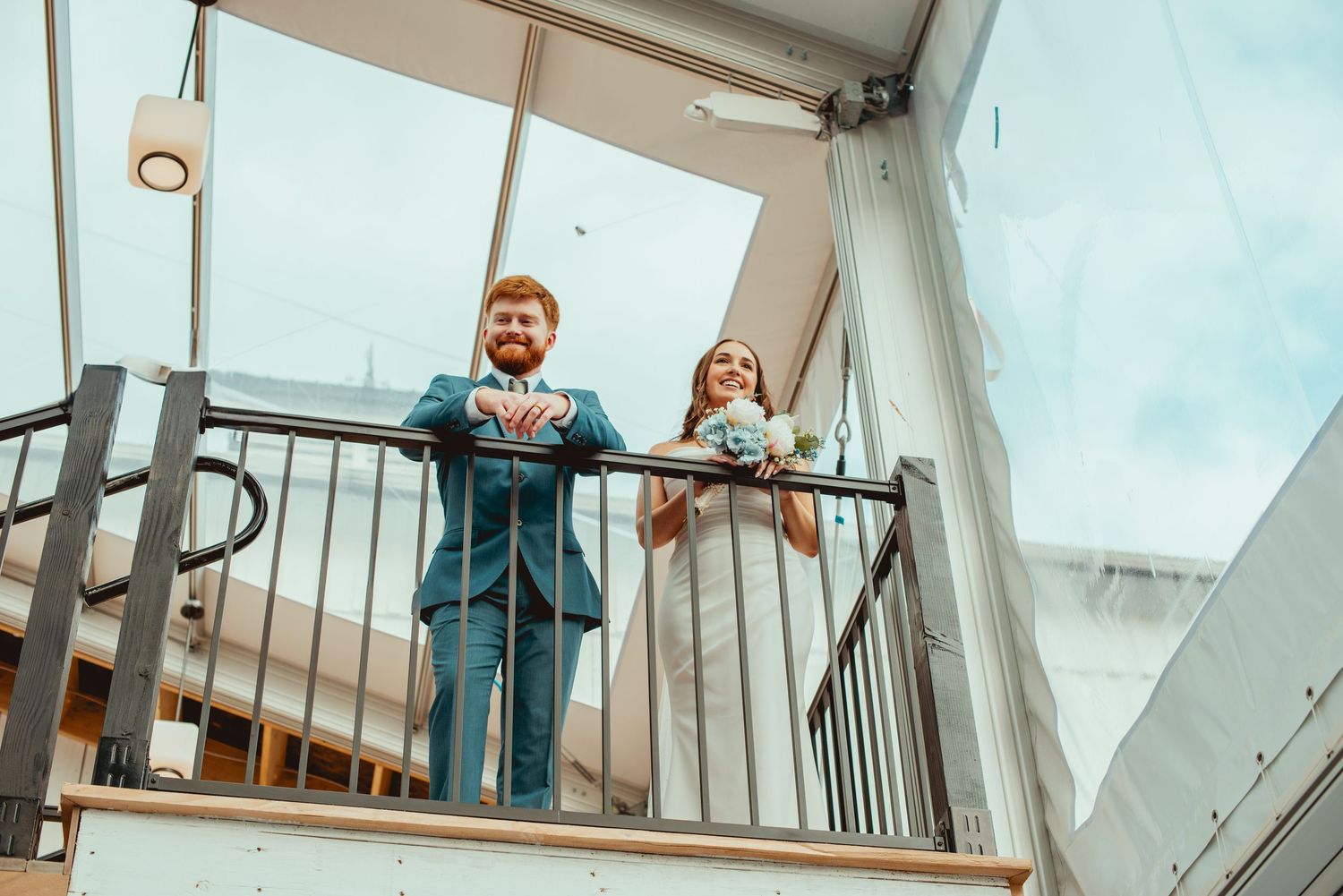 Wedding celebration inside bright conservatory style venue with glass ceiling.