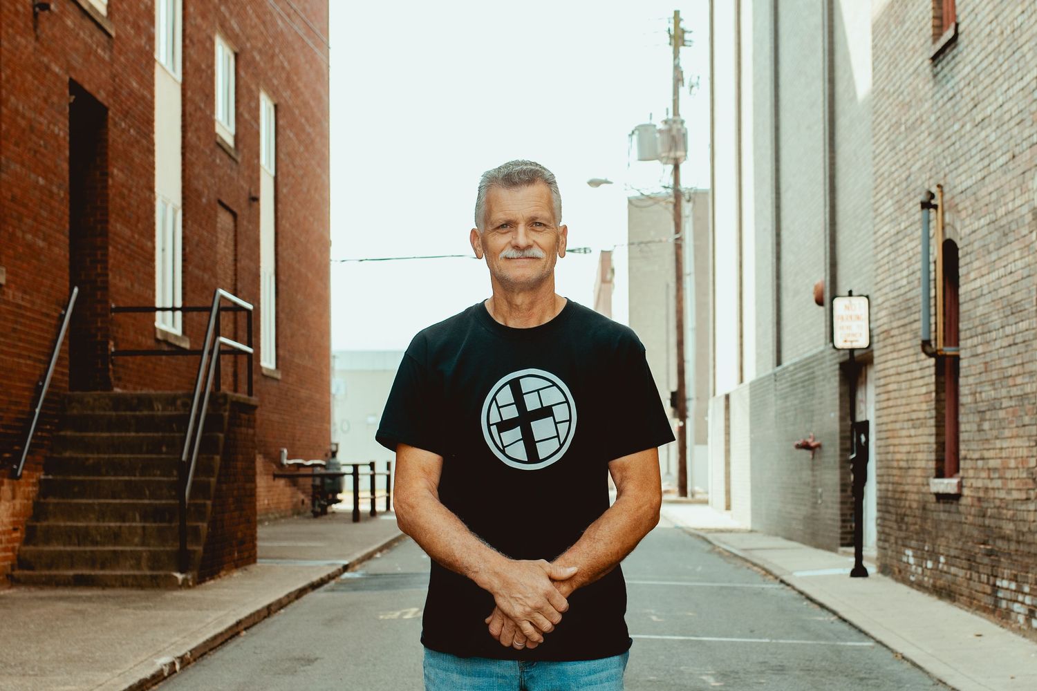 A series of black and white photographs showing a person in a dark shirt standing in various architectural spaces.