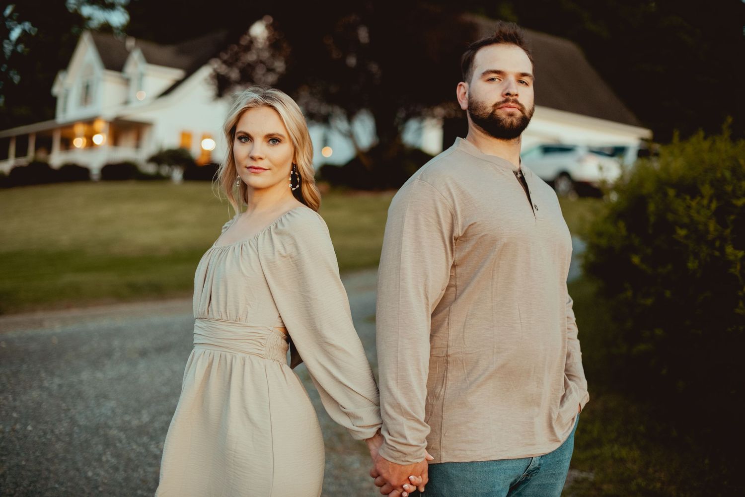 Couple walks hand in hand through outdoor setting during golden hour photoshoot.