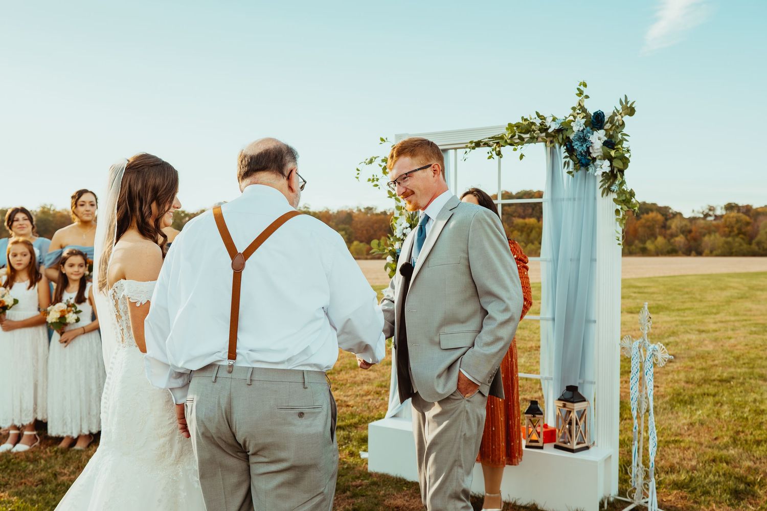 Wedding celebration in a scenic outdoor setting with decorative white arch and natural landscape.