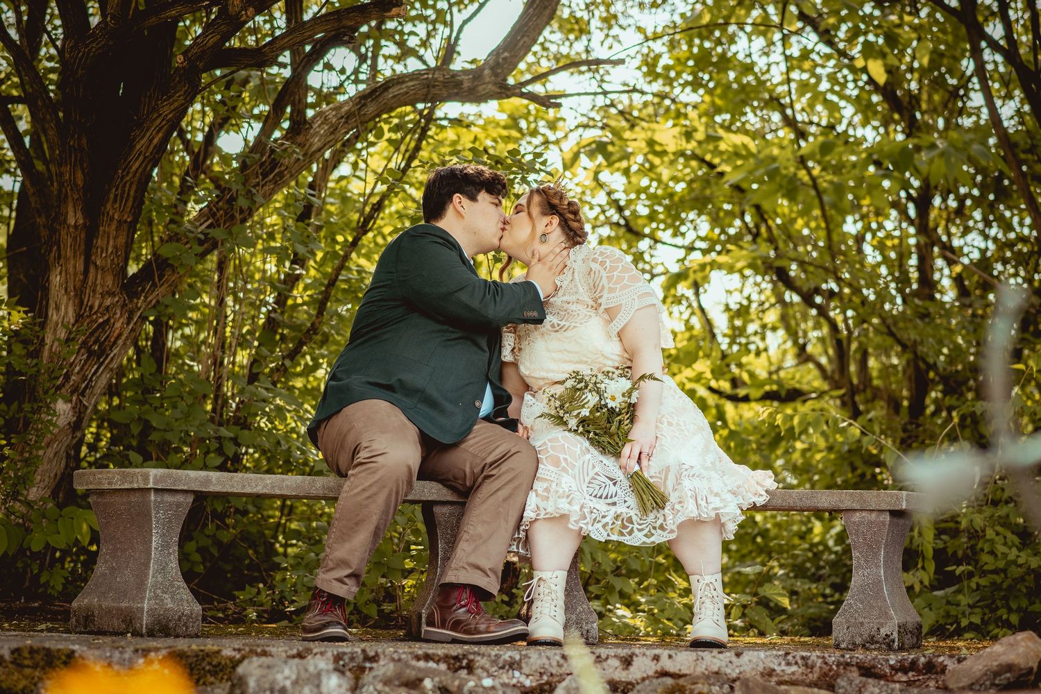 A rustic wooden bridge walkway surrounded by lush green trees and foliage in a natural setting.