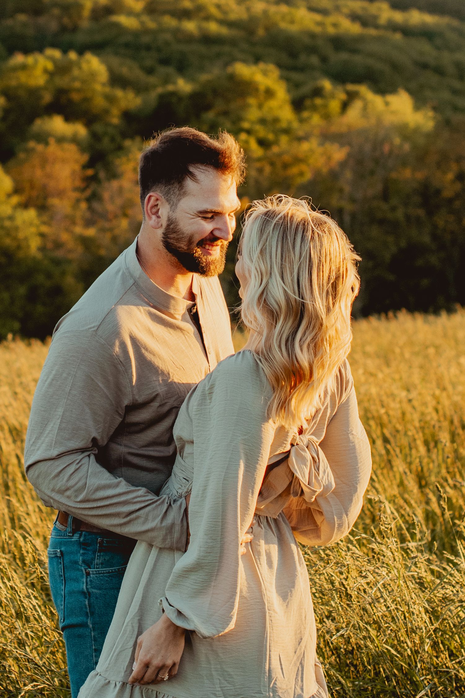 A couple embraces in a golden field at sunset with warm autumn lighting creating a romantic atmosphere.