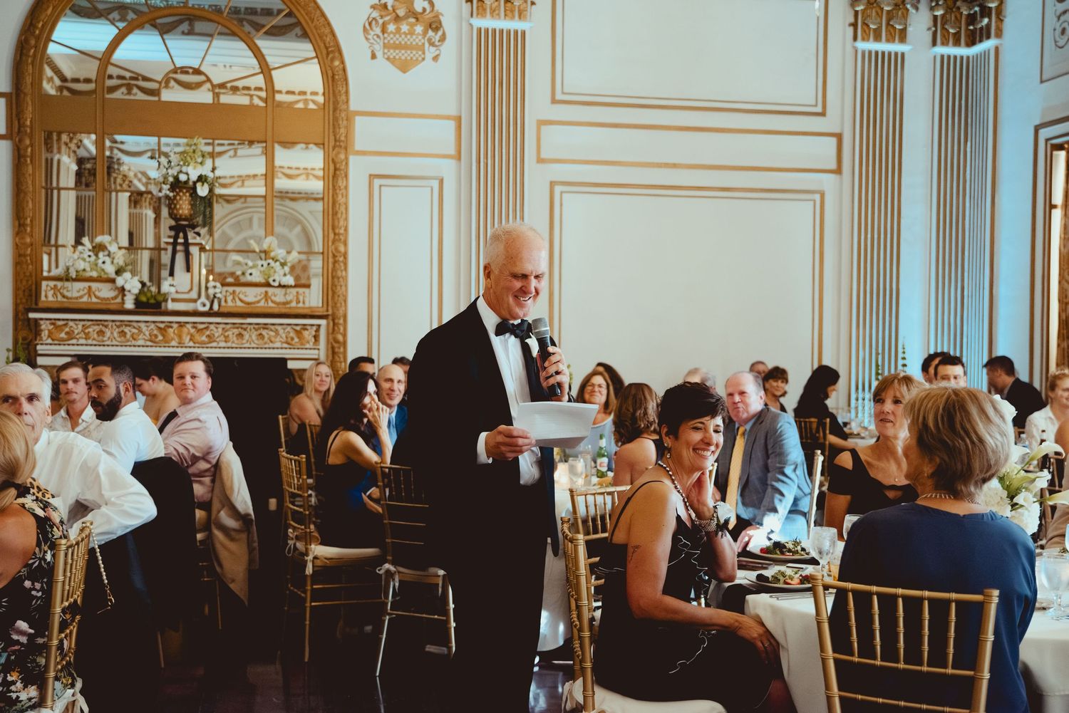 Elegant wedding reception in a grand ballroom with ornate architectural details.